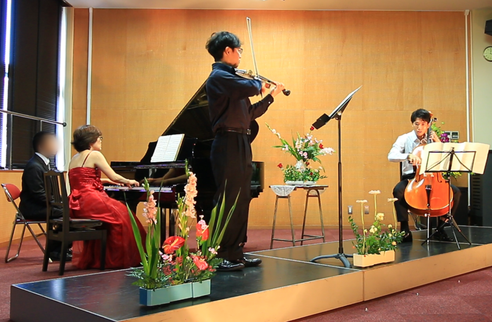 舞台上でバイオリンとチェロ、そしてグランドピアノを奏でる市川先生
